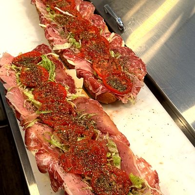 Two long rolls open on the counter, piled with sliced meats