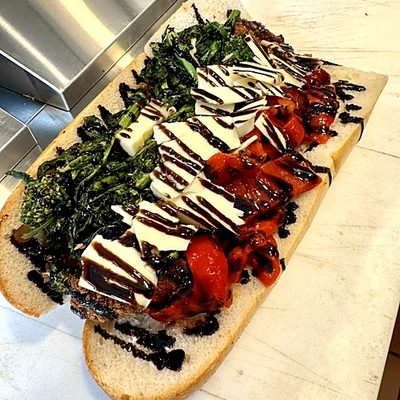 An open sandwich with broccoli rabe, fresh mozzarella, roasted red peppers and balsamic glaze