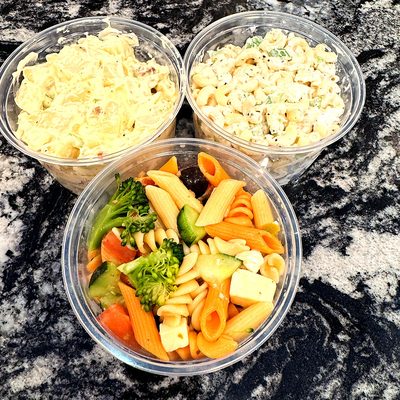 Macaroni salad, potato salad and pasta salad in to-go containers