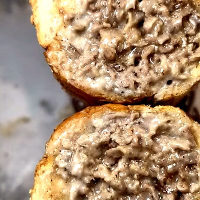 A cheesesteak cut in half: chopped steak and melted cheese on a toasted roll