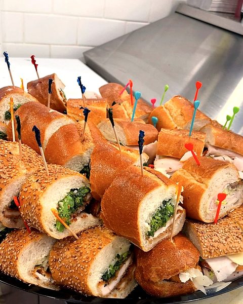A party tray of hoagies cut into pieces and held with picks