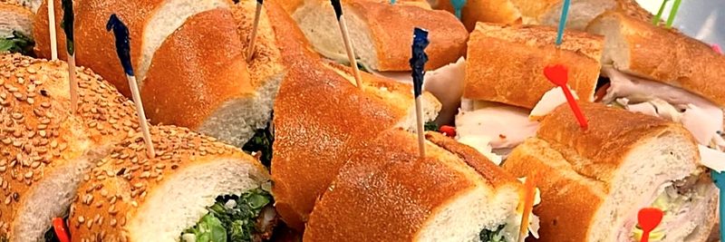 A party tray of hoagies cut into pieces and held with picks